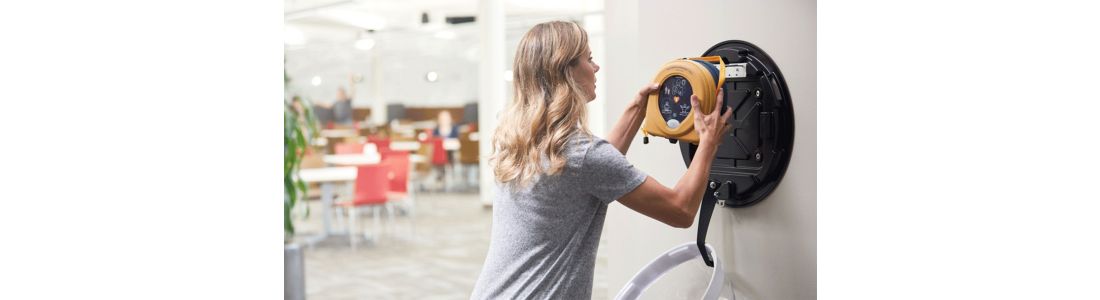 Woman getting AED device from wall