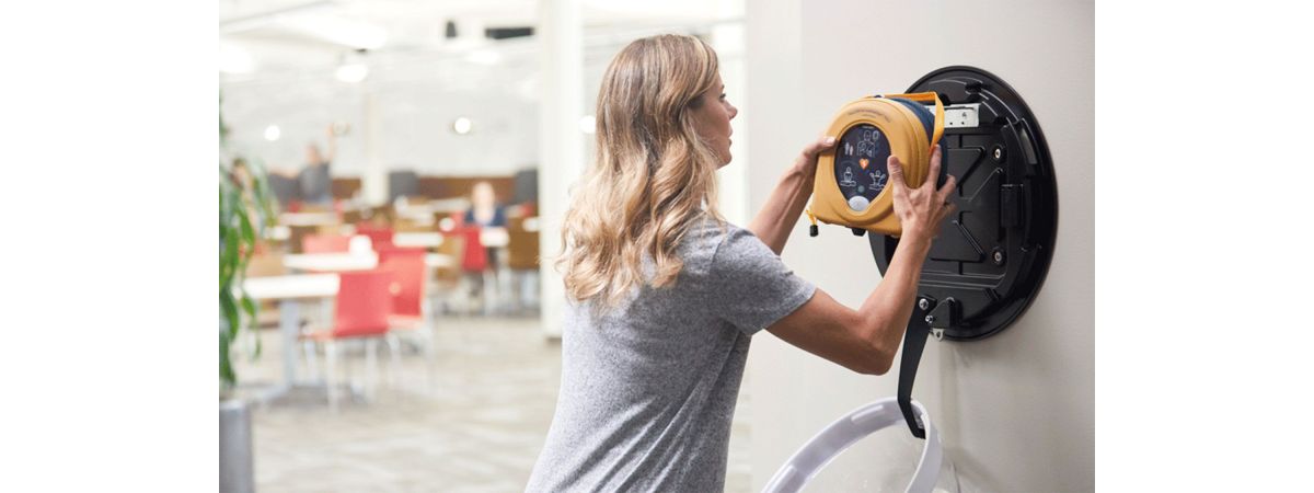Woman getting AED device from wall