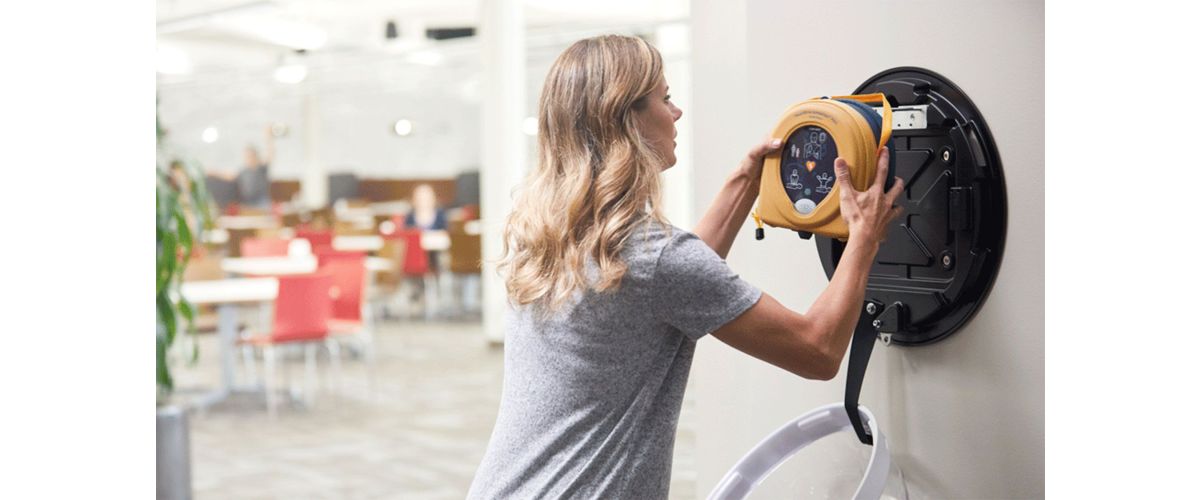 Woman getting AED device from wall