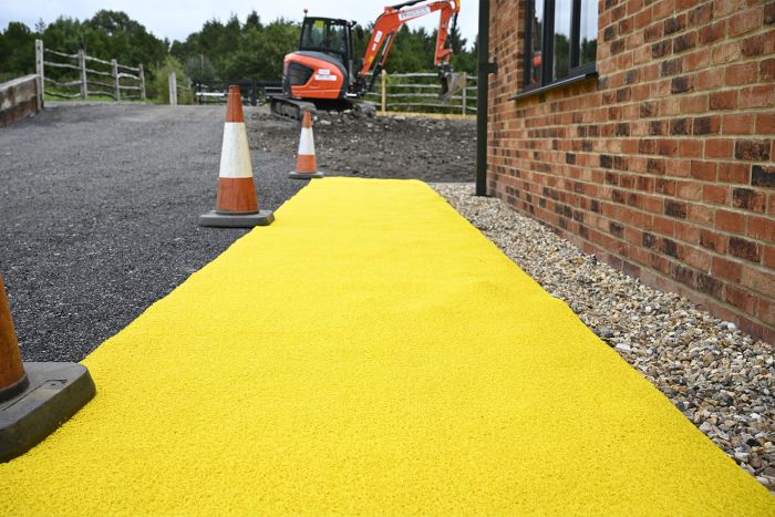 Yellow anti-slip spaghetti matting deployed as a temporary walkway on a UK construction site