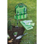Expert aluminium garden tool set in use outdoors, with green storage bag, kneeler, gardening gloves, hand fork and trowel arranged beside a flower bed.