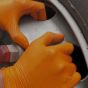 Orange nitrile diamond grip gloves worn on hands showing grip on oily automotive component | CMT Group UK