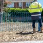 Blue mesh barrier fencing installed on construction site attached to steel fencing pins | CMT Group UK